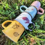 Tazas de colores con ilustraciones sobre el cesped